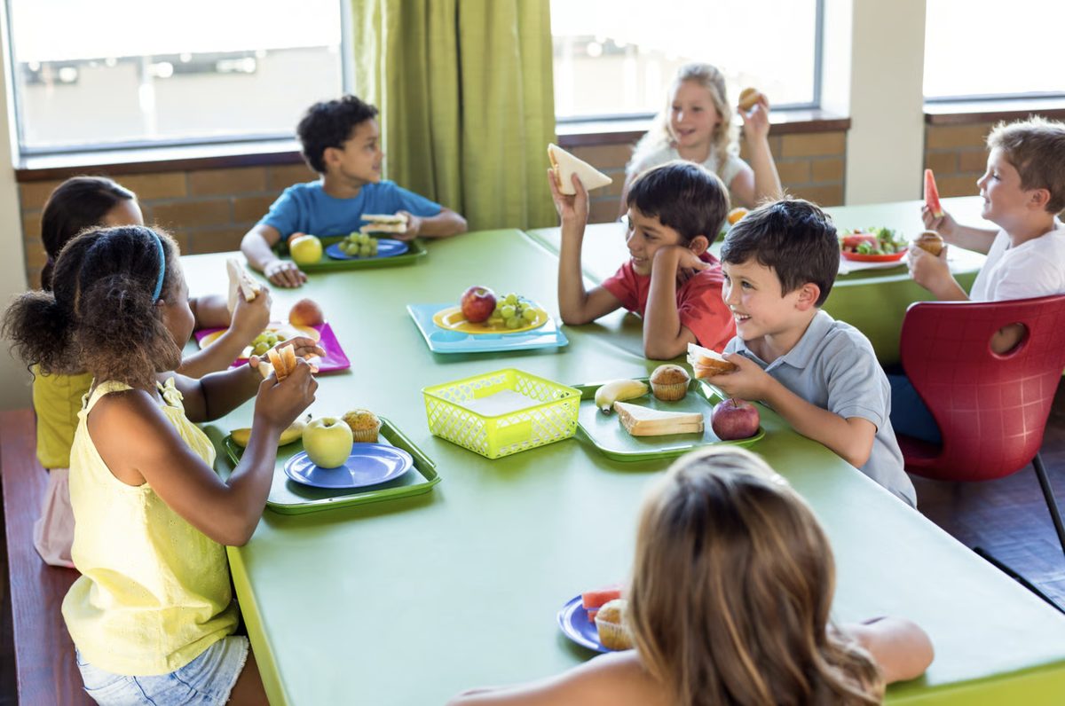 Children eating lunch together at a school cafeteria table