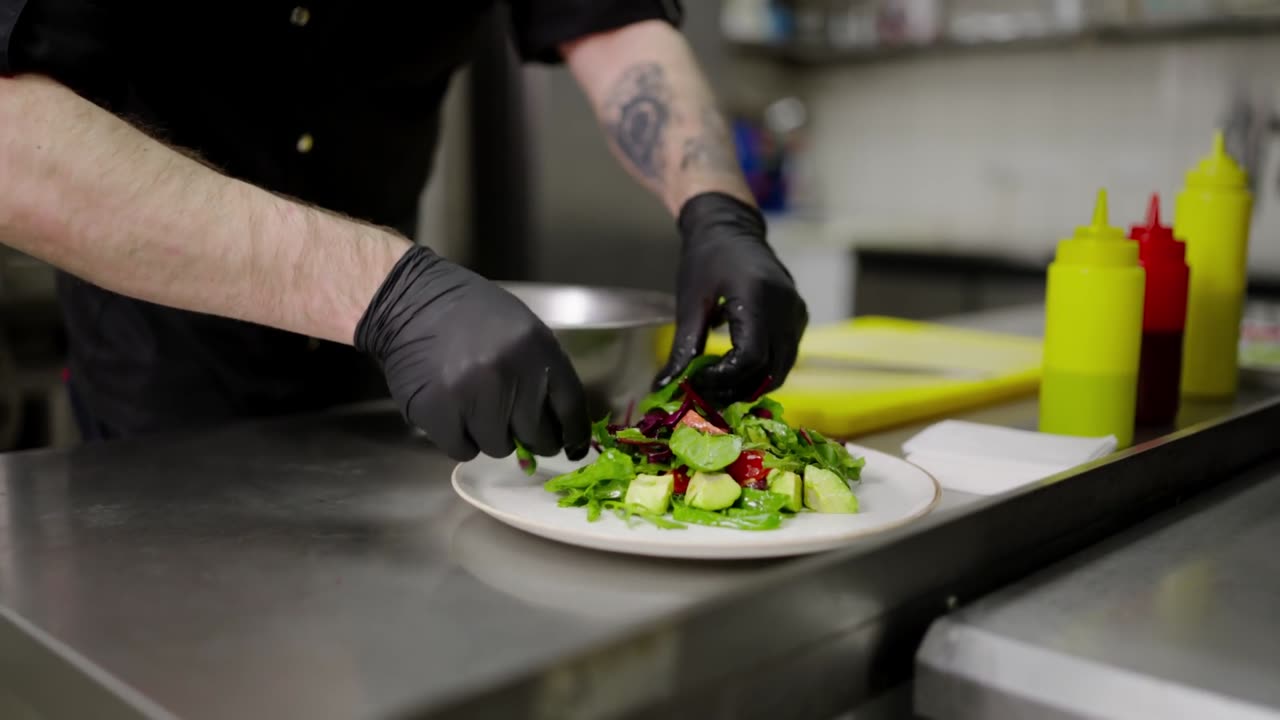 Brand video: gloved hands plating a salad at a commercial kitchen pass